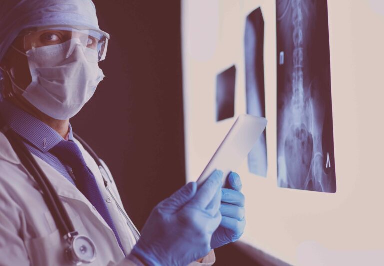 Imagem de um médico examinando radiografias de quadril em um ambiente hospitalar, representando avaliação clínica para artrose no quadril.