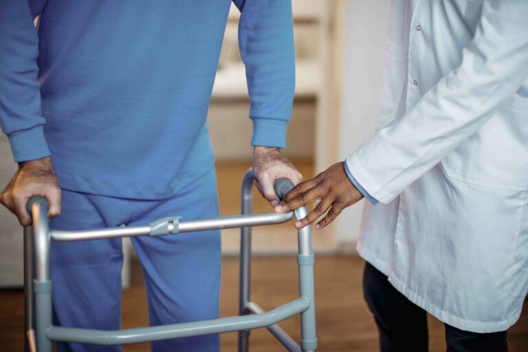 Paciente usando andador sob supervisão médica durante a recuperação de cirurgia de prótese de quadril.