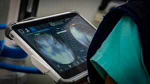Profissional da saúde observando radiografias de quadril em tela digital durante avaliação clínica.